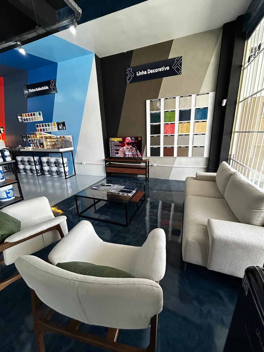 Lounge da linha decorativa dentro da loja, com piso em Cimento & Cor e mostruário na parede